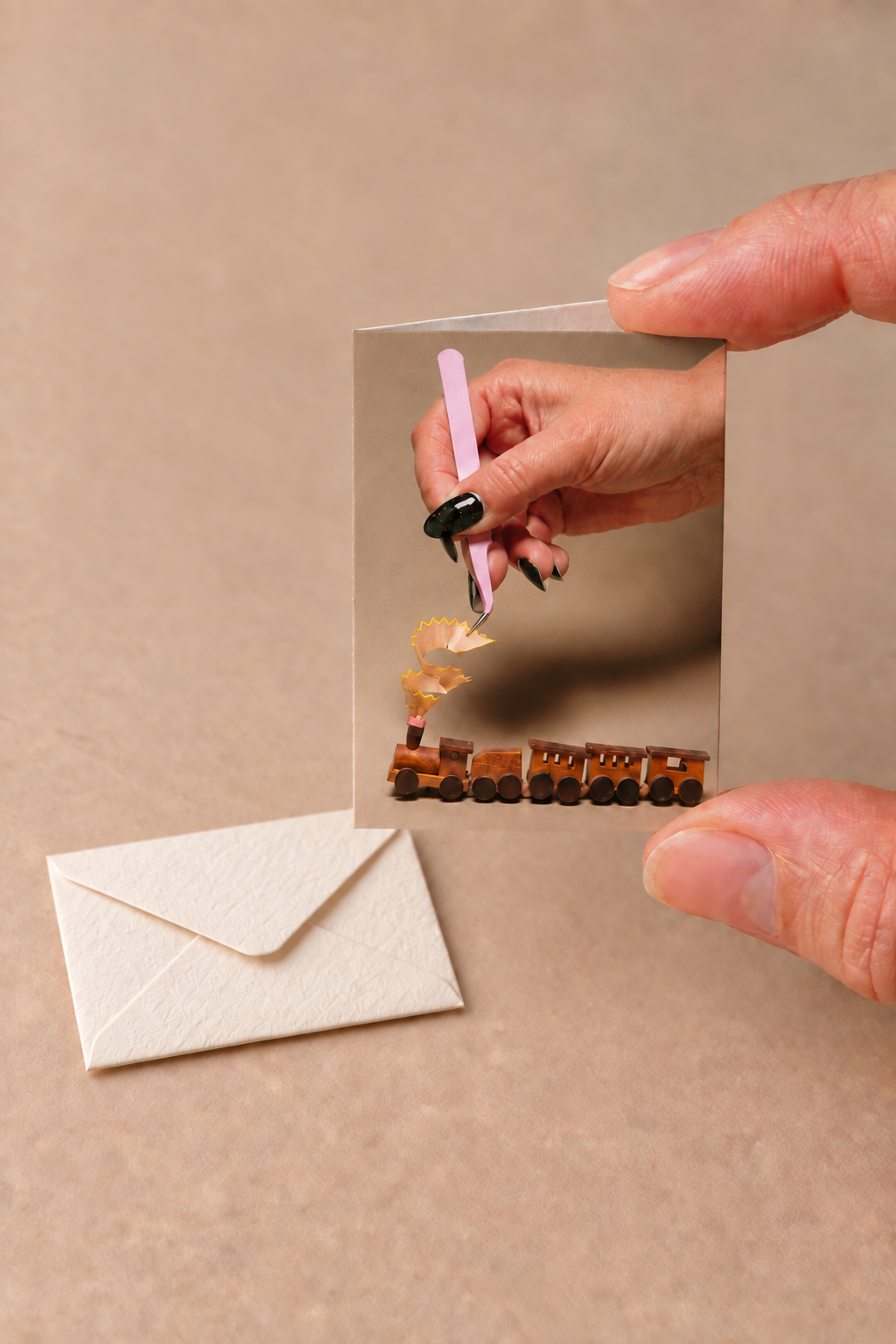 Tiny gift card featuring the wooden train, held above its miniature envelope